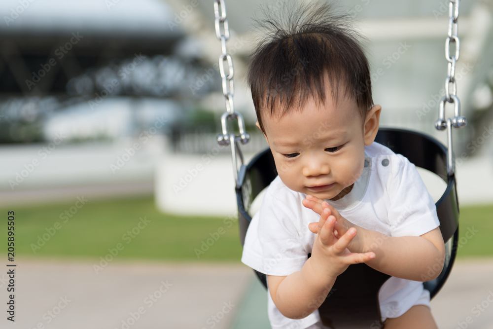 Adorable little Asian baby boy in swing at outdoor playground Adorable little Asian baby boy in swing at outdoor playground
