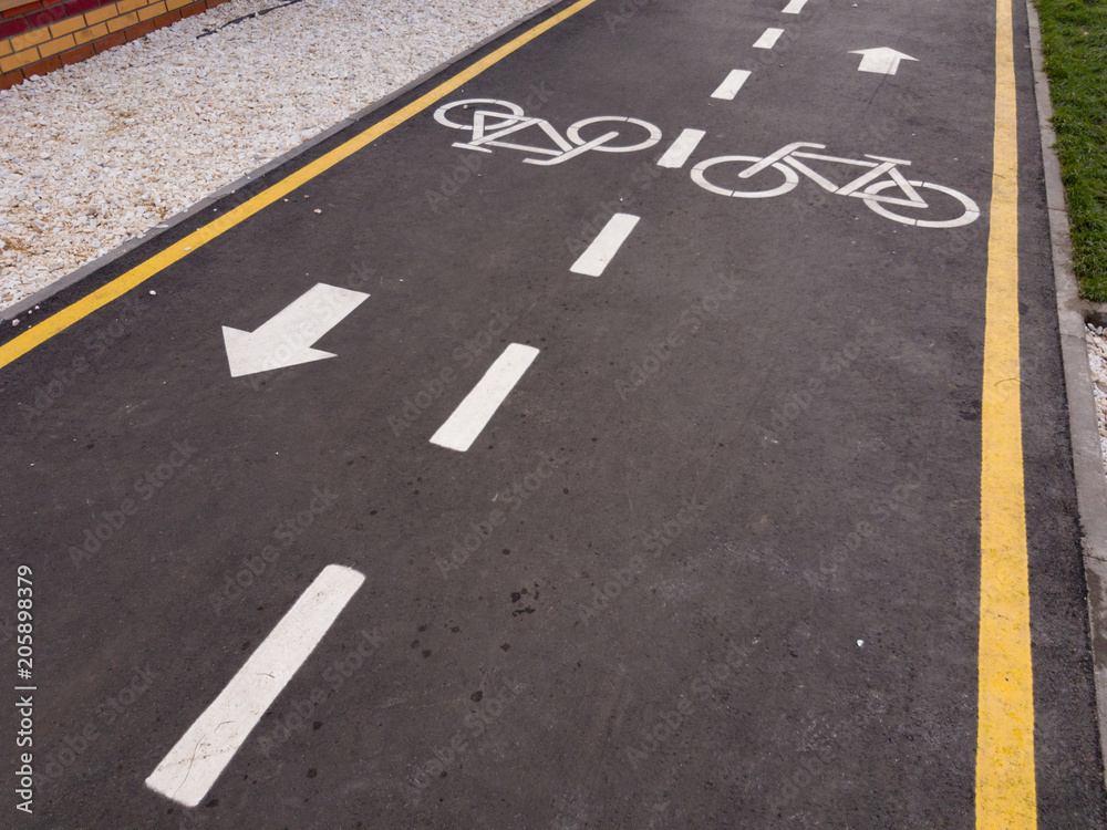 White bicycle sign with arrow on the asphalt, bike road sign on the street, bicycle lane sign on street, gray background White bicycle sign with arrow on the asphalt, bike road sign on the street, bicycle lane sign on street, gray background