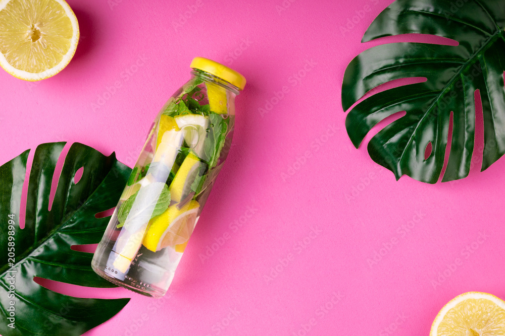Fotografie Bottle tropical water and monstera leaves on pink background