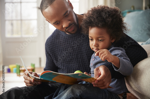 Obraz na plátne Father And Young Son Reading Book Together At Home