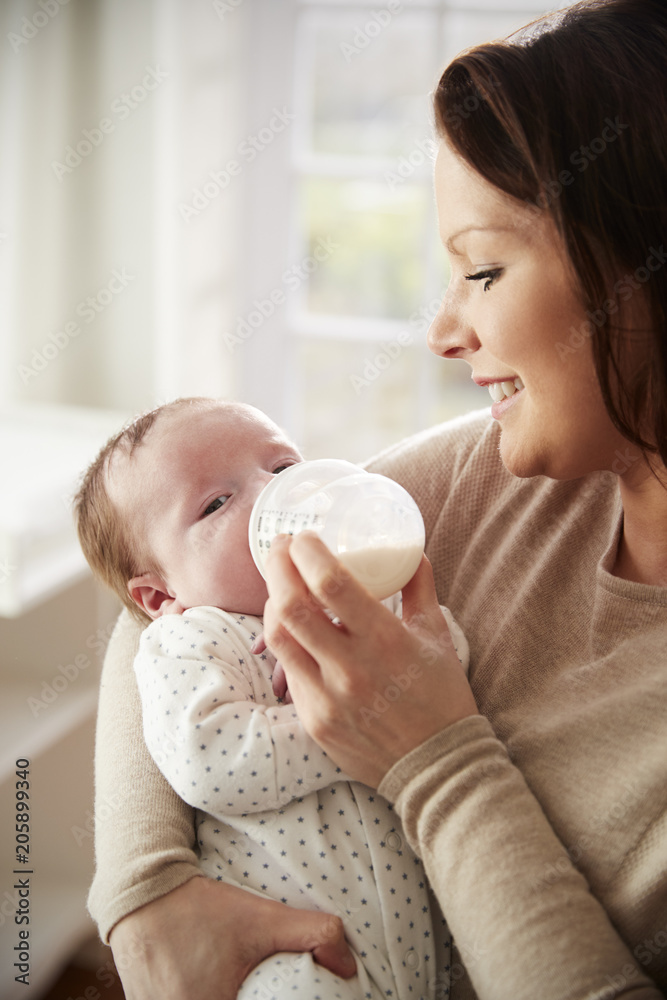 Mother Feeding Newborn Baby From Bottle At Home Mother Feeding Newborn Baby From Bottle At Home