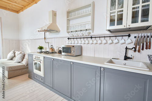 Fototapeta Naklejka Na Ścianę i Meble -  Wide angle shot of modern open living room with grey kitchen counters and white furniture in minimalistic Scandinavian design, copy space