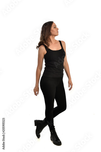 full length portrait of brunette girl wearing black singlet, jeans jeans and boots. standing pose, isolated on white studio background.