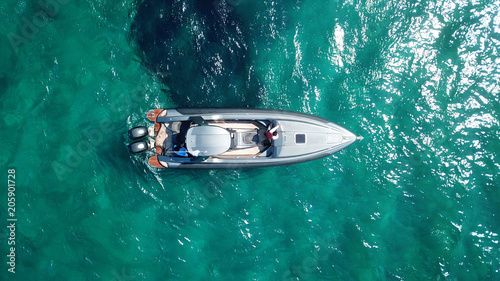Aerial photo of luxury speed boat docked in tropical island with emerald crystal clear waters