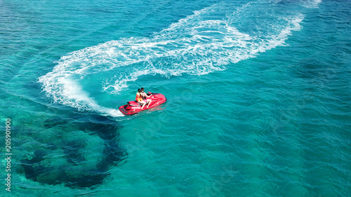 Aerial bird's eye view of jet ski cruising in high speed in turquoise clear water sea