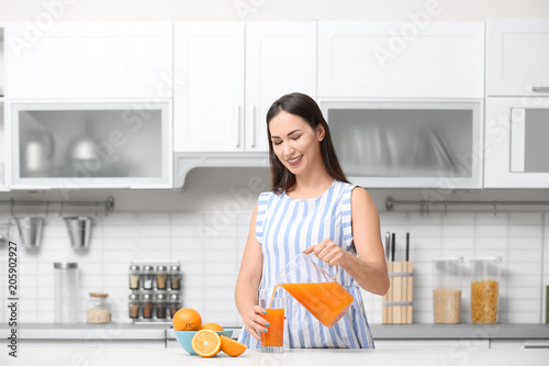 Young woman pouring orange ...