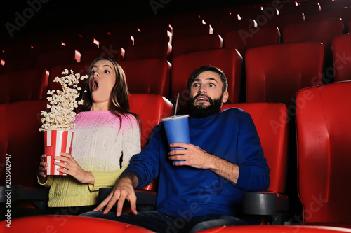 Emotional young couple watching movie in cinema