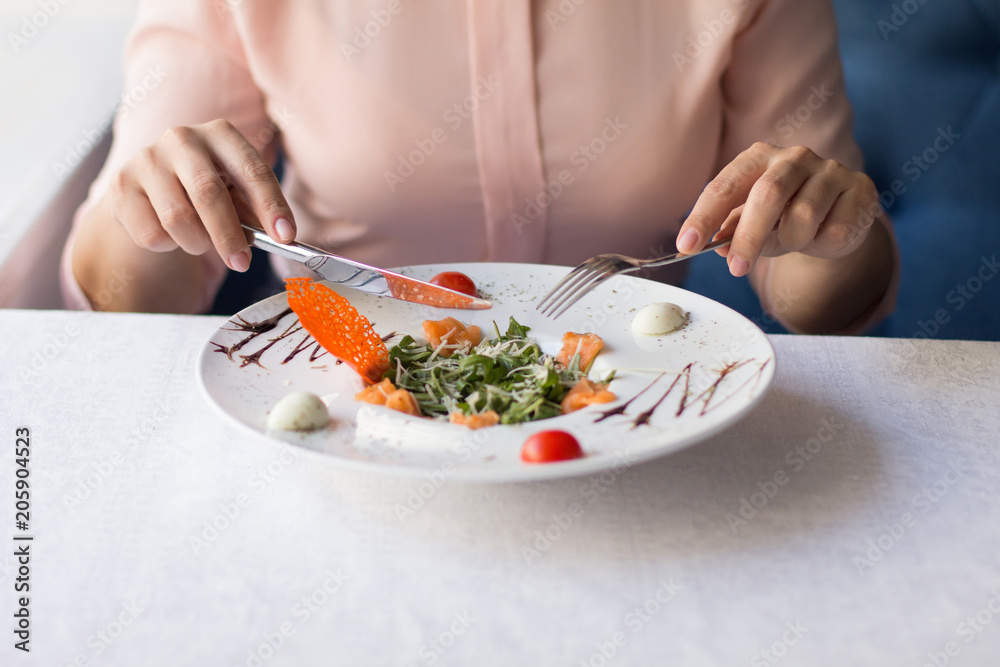 Close up of woman having lunch. Holding fork and knife.