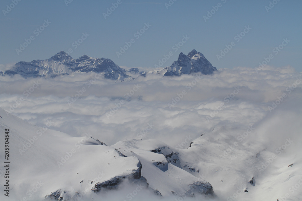Majestical scene with ice mountains with snowy peaks middle of clouds, Landscape with beautiful high rocks and dramatic cloudy sky in clear blue bright day Majestical scene with ice mountains with snowy peaks middle of clouds, Landscape with beautiful high rocks and dramatic cloudy sky in clear blue bright day