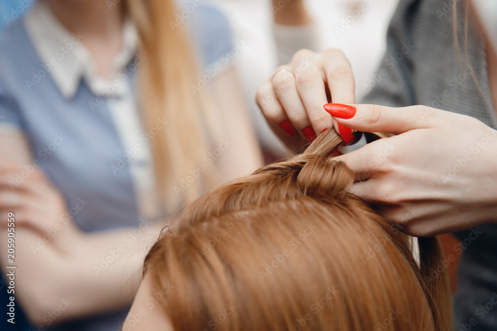Hairdresser does hairstyle for woman to weave braids, styling. Concept wedding specialist, workshop, training. Hairdresser does hairstyle for woman to weave braids, styling. Concept wedding specialist, workshop, training.