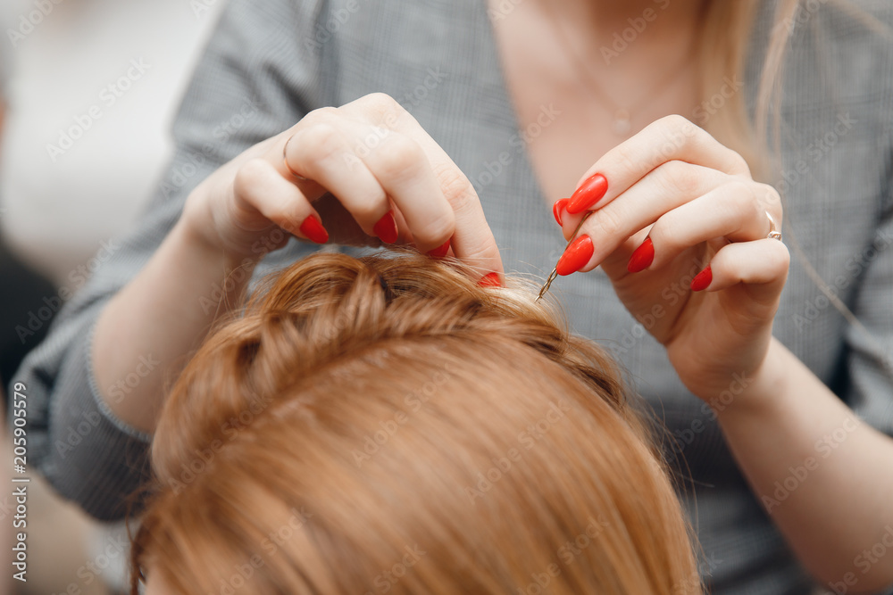 Naklejka premium Hairdresser does hairstyle for woman to weave braids, styling. Concept wedding specialist, workshop, training.