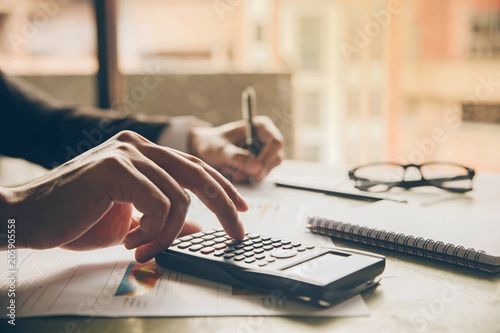 Close up hands businessman doing finances with using calculator and writing note in office. photo