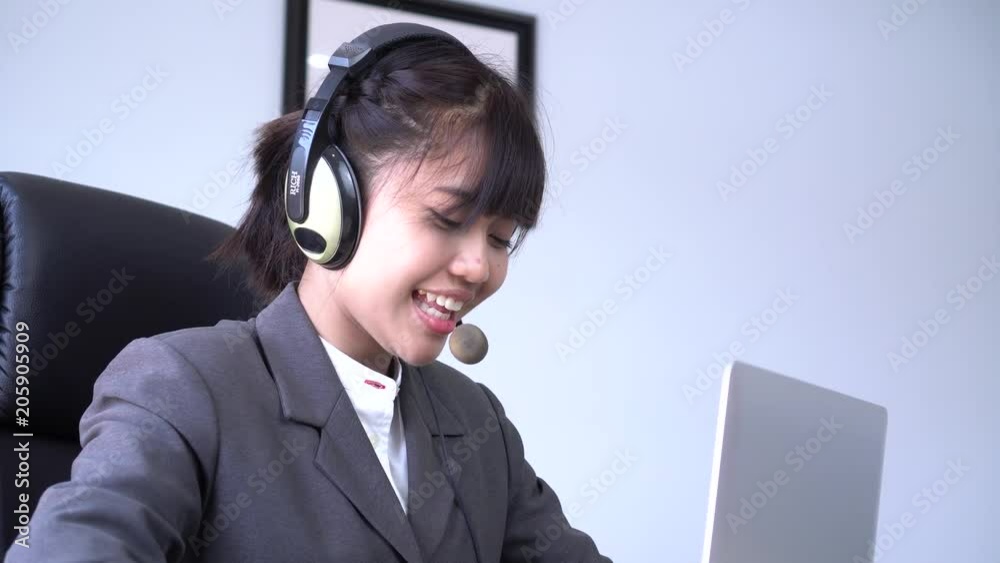 Asian Young woman friendly operator or call center agent with headsets working in call centre. Smiling to customer support operator at her computer at work office. Asian Young woman friendly operator or call center agent with headsets working in call centre. Smiling to customer support operator at her computer at work office.