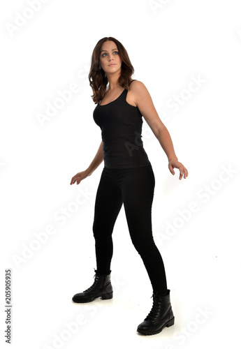 full length portrait of brunette girl wearing black singlet, jeans jeans and boots. standing pose, isolated on white studio background.