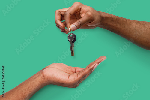 Black man handing key over to person hand photo