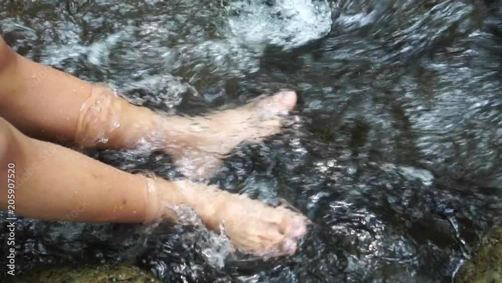 Relaxing for life, natural therapy concept : Young man's feet standing on rocks with clear, cold water. Feel comfortable and relax in nature of forest with water flowing on summer day, slow motion Relaxing for life, natural therapy concept : Young man's feet standing on rocks with clear, cold water. Feel comfortable and relax in nature of forest with water flowing on summer day, slow motion