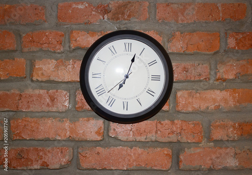 Round clock on a brick wall background