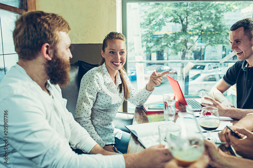 Young cheerful people smile and gesture while relaxing in pub. photo