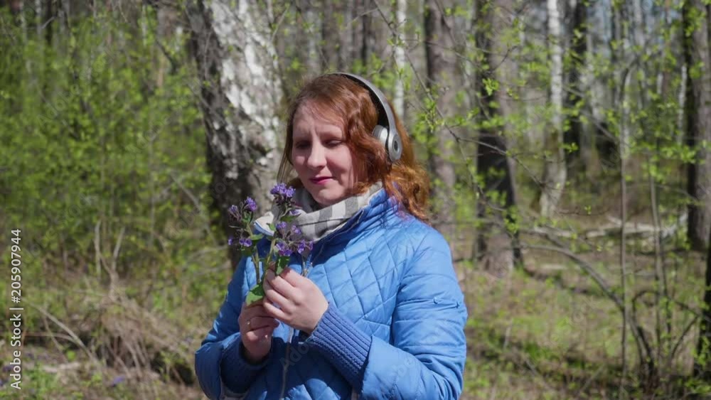A young girl in the Park, wearing headphones to listen to music. Woman enjoying music in headphones. A young girl in the Park, wearing headphones to listen to music. Woman enjoying music in headphones.