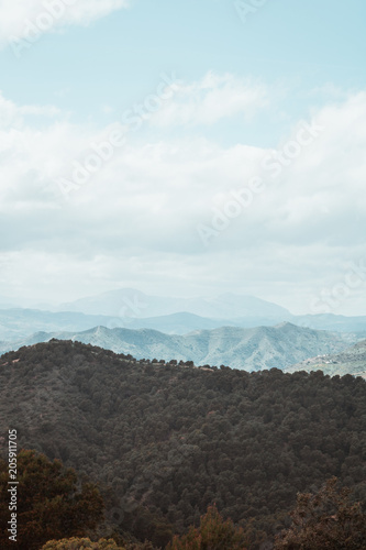 Mountains with trees and the silhouette of a mountain in the distance