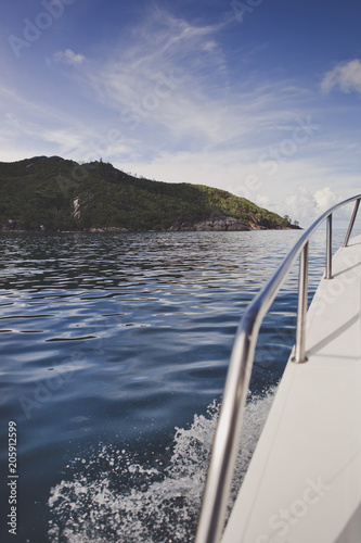 View of the green island from the yacht white deck. Blue sky. Vertical photo. © Irina Polonina