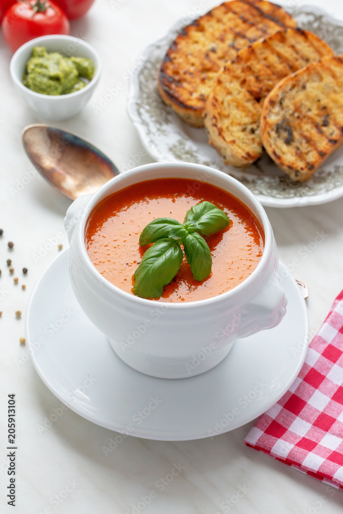 Fresh homemade tomato soup with fresh grilled Italian bread. Perfect lunch or dinner. On white table. Natural light, selective focus. Fresh homemade tomato soup with fresh grilled Italian bread. Perfect lunch or dinner. On white table. Natural light, selective focus.