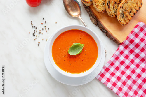 Fresh homemade tomato soup with fresh grilled Italian bread. Perfect lunch or dinner. On white table. Natural light, selective focus.