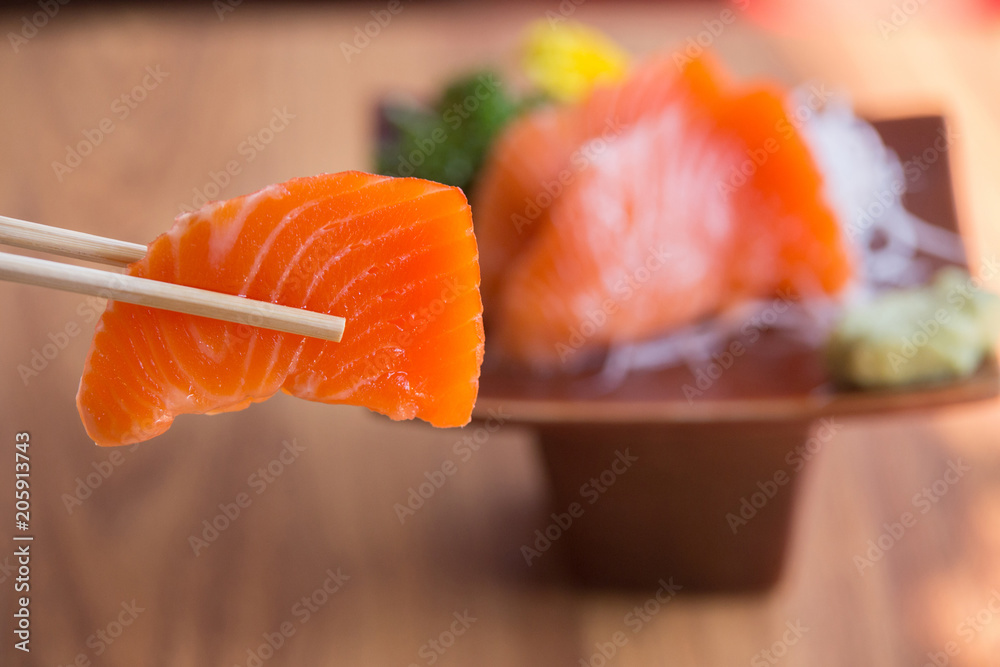 Salmon sashimi with Wasabi on the brown plate on a wooden table.Japanese Food Salmon sashimi with Wasabi on the brown plate on a wooden table.Japanese Food