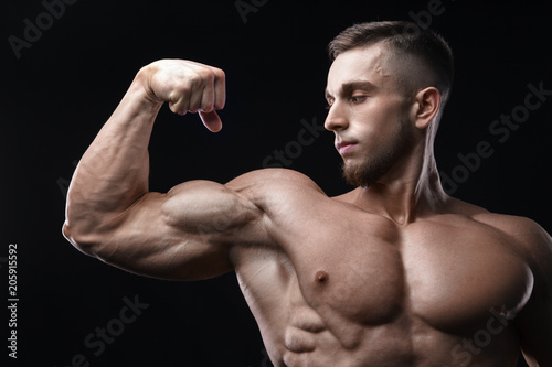 Handsome power athletic man bodybuilder demonstrates his biceps.