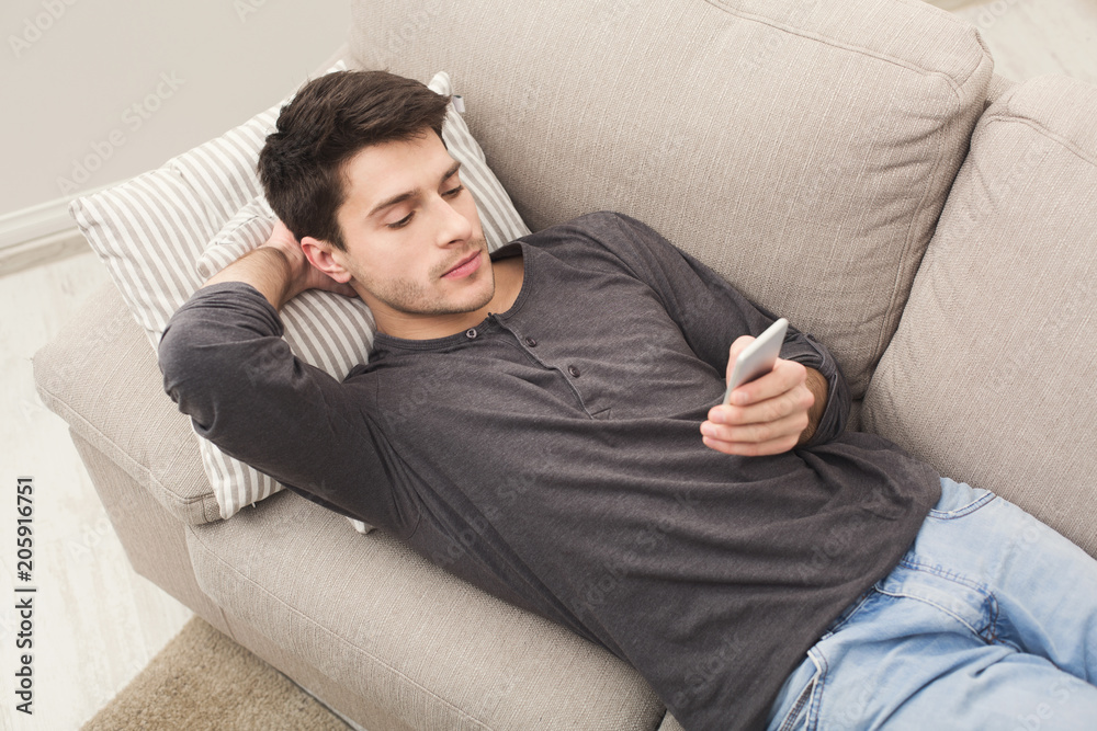 Young man messaging on smartphone at home