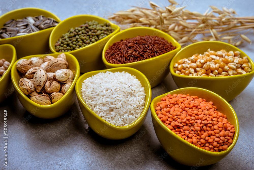 Different grains, seeds, beans in ceramic bowls on grey concrete table Different grains, seeds, beans in ceramic bowls on grey concrete table