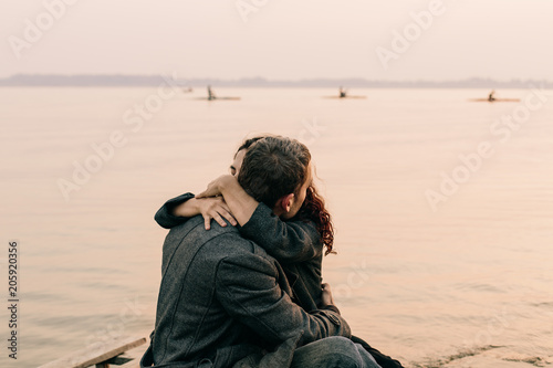 couple hugging and kissing on a pier