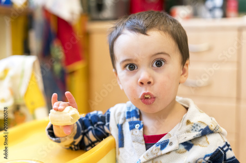 Boy 2 years old eating banana. Baby 2 years old eating a banana in the kitchen photo