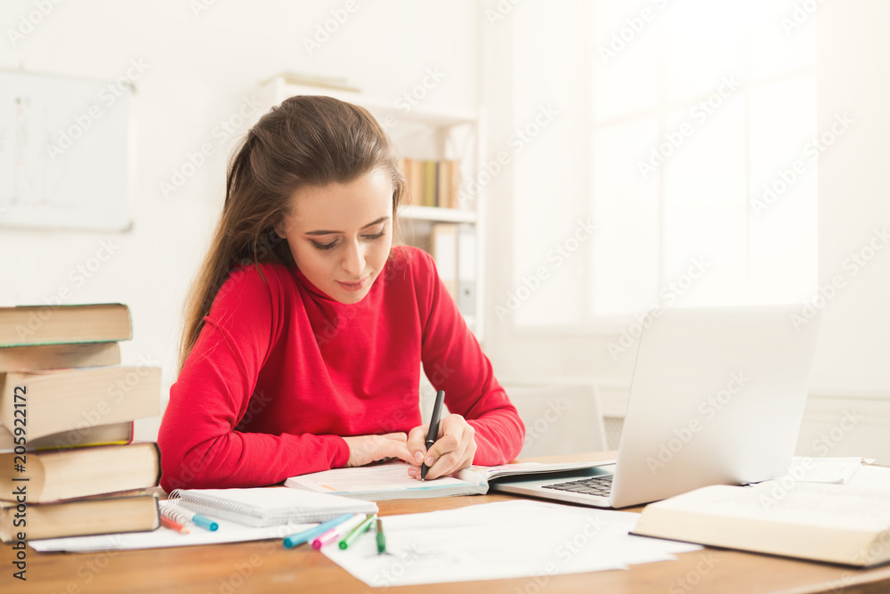 Student girl studying at table full of books Student girl studying at table full of books