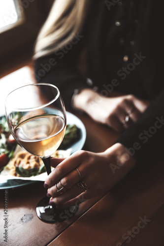 Female hand with glass of wine and food in the background