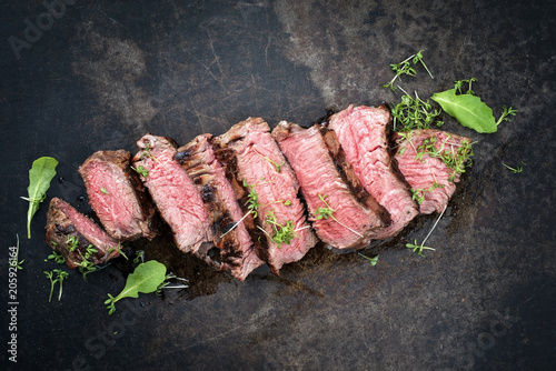 Barbecue Wagyu Hüftsteack aufgeschnitten mit Salat und Kräuter als Draufsicht  auf ein Board mit Textfreiraum photo