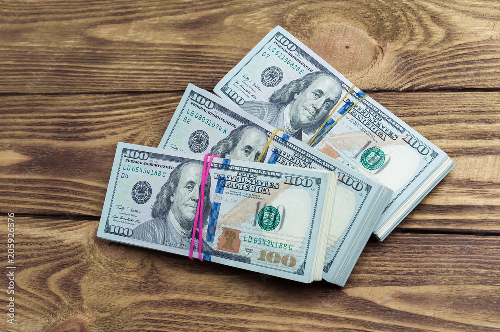 Dollars in three packs on a wooden table. Dollars in three packs on a wooden table.
