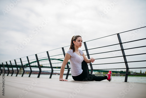 Girl relaxing while exercising outdoors at city quay.