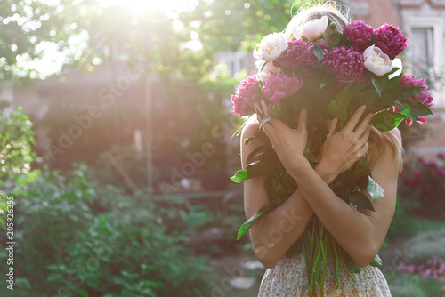 Obraz na płótnie girl in the garden with a big bouquet of peonies in hands at sunset w salonie