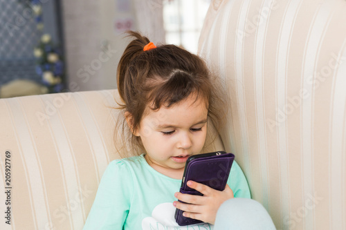 Little girl with smartphone in room