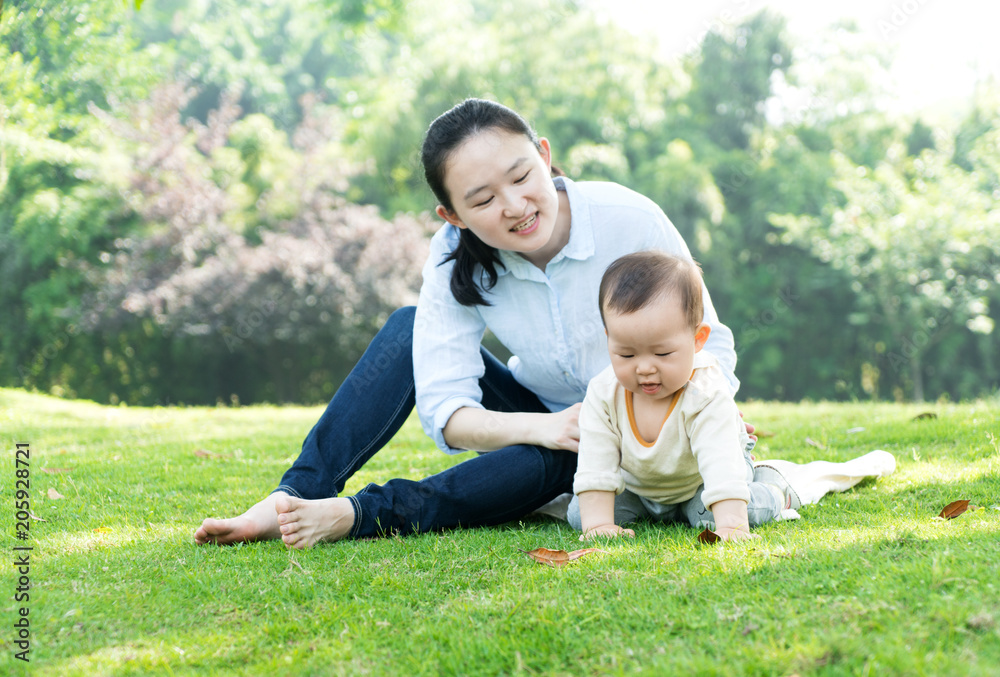Happy mother and baby sitting on meadow in park Happy mother and baby sitting on meadow in park