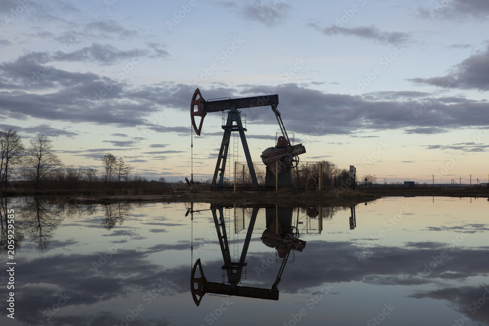 Naklejka premium Industrial pump jack, sunset in oil field