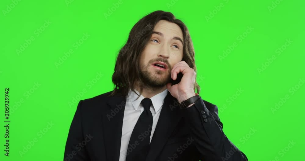 Close up of the young attractive businessman in the black suit and tie talking on the phone on the chroma key background. Green screen. Portrait shot Close up of the young attractive businessman in the black suit and tie talking on the phone on the chroma key background. Green screen. Portrait shot