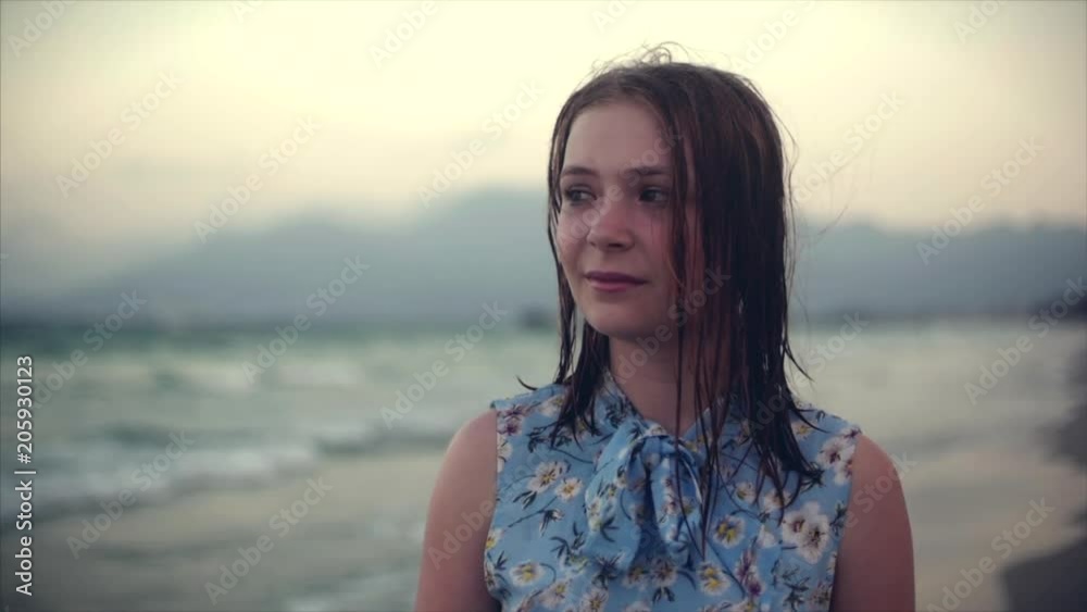 Close up portrait of European beautiful cute blonde young woman or girl with sad expression looking at camera, running hand through hair blowing in wind on tropical beach, slow motion Close up portrait of European beautiful cute blonde young woman or girl with sad expression looking at camera, running hand through hair blowing in wind on tropical beach, slow motion