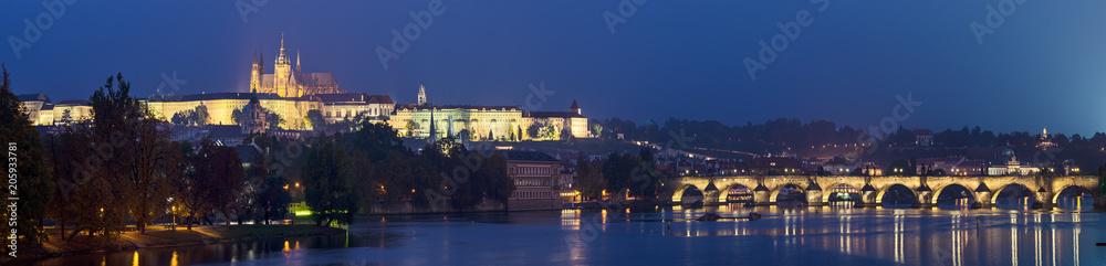 Obraz premium Night view of famous european Prague city - the capital of Czech republic with reflection in river Vltava and Charles Bridge. Panoramic view.