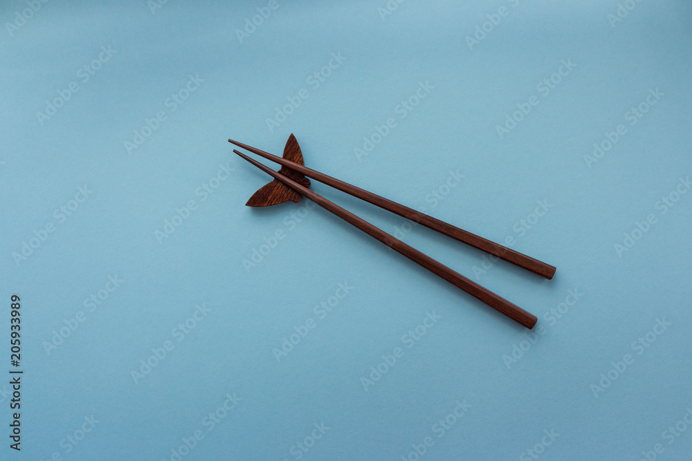 Pair of wooden chopsticks for japanese and chinese food on blue background with copy space. Travel and cuisine concept. Asia food culture concept. Sushi set of chopsticks. 