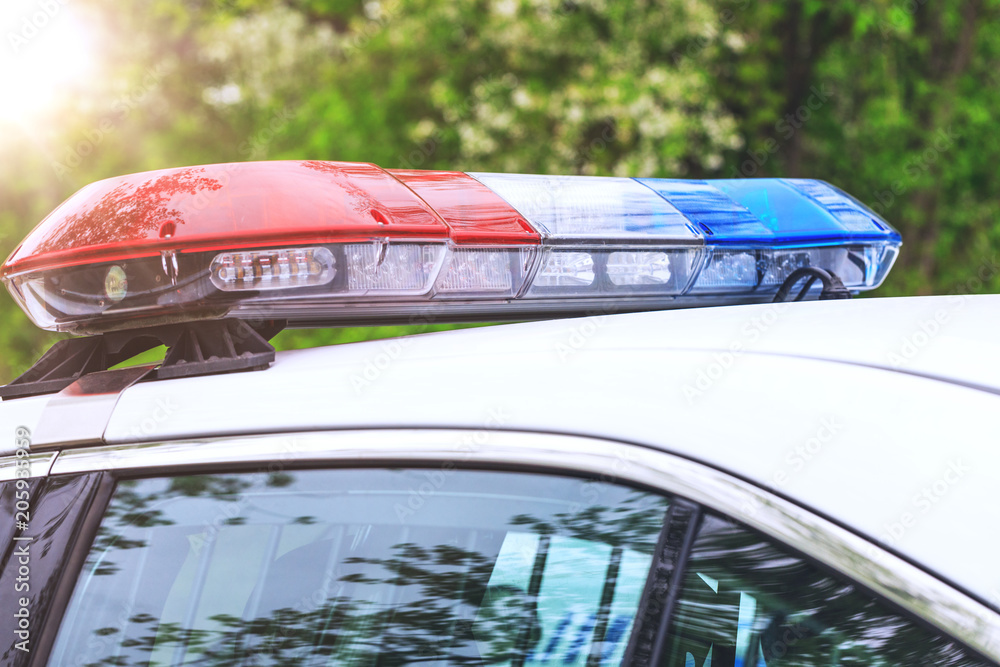 Obraz premium Police patrol car with sirens off during a traffic control. Blue and red flashing sirens of police car during the roadblock in the city.