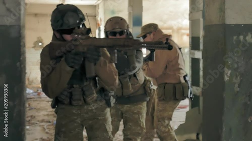 Soldiers in camouflage with combat weapons sneak along the corridors of the old building, the military concept photo