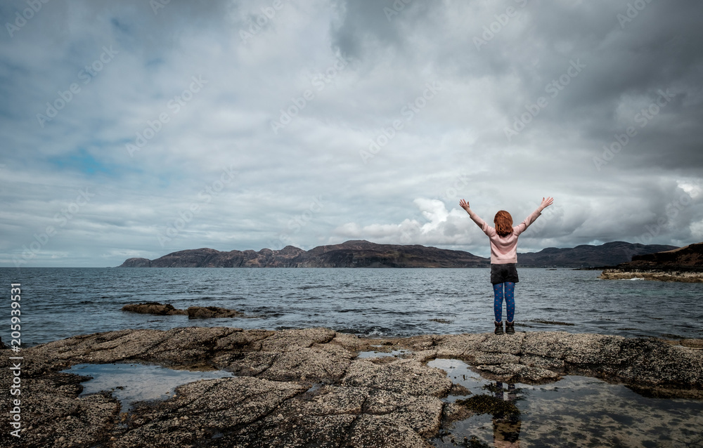 Girl with arms spread observing the views on the Scottish scenery on the Isle of Mull, Girl with arms spread observing the views on the Scottish scenery on the Isle of Mull,