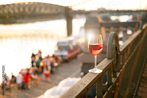 Photography Glass of red wine on a railing with sunset in a Prague city